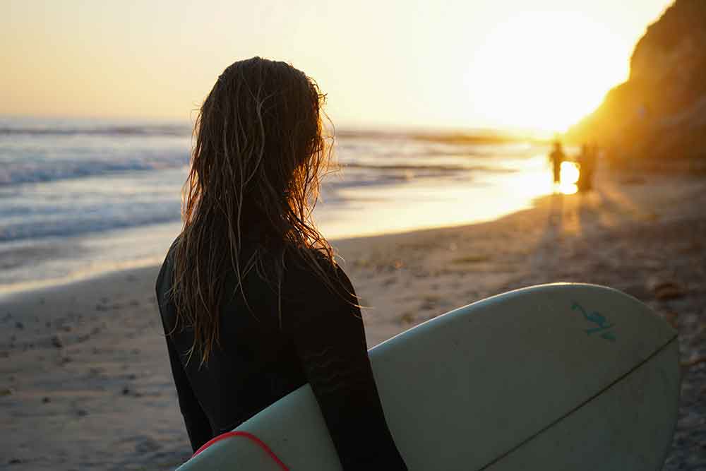 girl-holding-surfboard-on-the-beach 